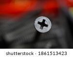 Macro close up of isolated grey crosshead screw head, blurred screws in tool box background (focus on upper part of screw head)