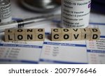 Small photo of Viersen, Germany - June 1. 2021: Closeup of word long covid on laboratory requisition slip with syringe and vial (selective focus on upper right part of text block with letter C)