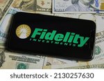 Small photo of Viersen, Germany - January 9. 2022: Closeup of mobile phone with logo of fidelity investments, us dollar paper banknotes background