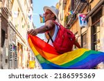 A gay black man walking in the pride party with an LGBT flag visiting the city