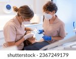 Dentist and assistant examining the mouth of a patient lying on the chair of a clinic
