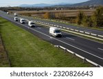 Four White delivery van on the highway. White modern delivery small shipment cargo courier van moving fast on motorway road to city urban suburb. The world's best transport of goods.