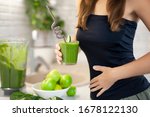 Small photo of woman holds a glass of green smoothie and a hand on her waist, showing how she has lost weight and improved digestion. Morning detox for a healthy lifestyle, weight loss, ketone diet, raw food diet