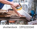 Small photo of Carpenter using backsaw hand tool cutting wood plank at outdoor workshop.