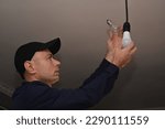 Small photo of the electrician unscrewed the incandescent lamp and replaced it with an LED lamp. the concept of energy economy