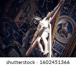 Jesus Christ nailed on a large wooden crucifix at Albi Cathedral with Renaissance frescoes of church ceiling in the background. Religious statue, Tarn department of Occitanie, France