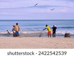 Small photo of Cartagena, Bolivar Colombia - 1 February 2024: fishermen collecting the trammel net after finishing fishing on the seashore on the beaches of Cartagena