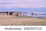 Small photo of Cartagena, Bolivar Colombia - 1 February 2024: Group of fishermen gathering the nets on the beach of Cartagena on the seashore to collect the fish caught in the trammel.