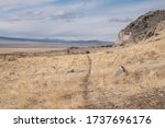 stock-photo-a-trail-leading-across-a-desert-valley-covered-in-golden-colored-grass-under-a-cloudy-sky-1737696176.jpg