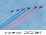 Group of military aircrafts flies in formation with three colored smoke in shape of russian flag in the sky during Victory Day parade in Russia.