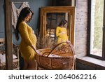 Small photo of pregnant woman stands by a wicker cradle. Baby bassinet made of natural wooden materials. Eco parenting. Baby cot preparation for birth of a child. Stylish modern boho interior. Waiting for childbirth