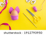 Make a crochet rabbit with ears from yarn, step 15 DYI Easter egg in purple crochet bunny costume on yellow background, decoration concept for Easter, creative decoration