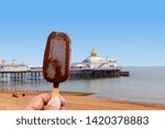 Hand holding a choc ice lolly at the seaside