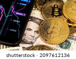 Bitcoin BTC Cryptocurrency Coins and US Dollar banknotes next to mobile phone showing candlestick chart graph. Background with Cryptocurrency Bitcoin and US Dollar. Stock market concept. BTC to USD 