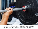Small photo of Weightlifting. The process of bench press with the wrong grip. Inept handling of the barbell during the exercise. Close-up. unrecognizable person