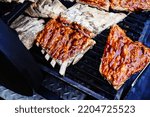Small photo of Unappetizing ribs in sauce are located on the grill. Cooking meat on fire and coals in a street cafe. Close-up. selective focus