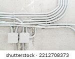 Electrical wiring in a protective corrugation on the wall. The wires and junction box are installed on a concrete surface. Close-up
