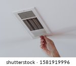 Handyman adjusting HVAC ceiling air vent. Air flow adjustment for overhead home heat and air conditioning ventilation duct.