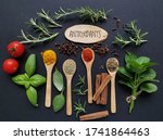 Set of various spices in wooden spoons and fresh herbs rich in antioxidants. Natural sources of antioxidants rosemary twigs, fresh green basil leaf, mint leaf, turmeric, clove, cinnamon, chili, tomato