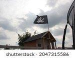 Wooden playhouse for children in the summer garden with a hanging pirate flag.