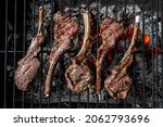 Small photo of Grilled lamb mutton chop steaks on barbecue, outdoor BBQ grill with fire. Top view.
