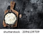 Mascarpone cream cheese in a pan for tiramisu. Black background. Top view. Copy space