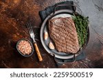 Grilled flank beef steak with herbs. Dark background. Top view.