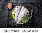 Raw Sea Bass fillet, Labrax fish with herbs and lime. Black background. Top view.