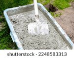 Small photo of Mixing, stirring cement slurry, concrete rubble mortar with shovel in big bowl, reservoir, trough, bucket. Preparing for building process, renovation, laying foundation.