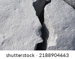 Small photo of A split rock has a large crack through it which makes it look like a crevasse