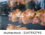 Small photo of Rows Of Hot Roasted Skewered Whole Rotisserie Chickens . Glass through view . Selective focus