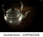 Small photo of White hot water kettle, formerly on a black background on a wooden table