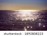 Glittery golden sea water during sunset with the sky looking blue and orange