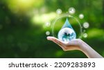 Small photo of Water drop in hand against natural background in Save water concept on world water day. Conserving the environment in terms of water resources