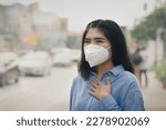 Small photo of Asian woman wearing the N95 Respiratory Protection Mask against PM2.5 air pollution and headache Suffocate. City air pollution concept