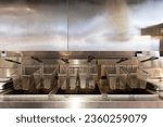 Small photo of Idle deep fryer baskets rest on stainless steel surface, marked with lingering grease stains.