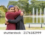 Small photo of Cheerful queer couple hugging in a park looking at the camera