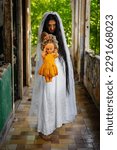 Small photo of Deranged bride with a doll in abandoned place. Inspired by the traditional American legend of la llorona (the weeping woman)