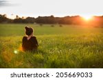 Portrait of a beautiful young woman or girl on very green meadow watching the sunset enjoying nature summer evening outdoors. Sunshine. Copy space.