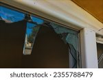 Small photo of A broken plastic window with the remaining fragments through which thieves entered and stole valuables. The concept of security, private property, looting, theft, robbers, refugees, riots, attacks.