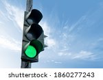 Traffic light in green color, with a blue sky and cloud in the background.