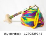 Small photo of Colorful acrylic fiber in the process of being spun by hand into yarn for knitting, crochet or some other crafty purpose. Yarn spindle and fiber on white background.