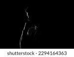 Male silhouette on a black background. A man stands thoughtfully on a black background