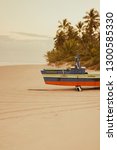 Small photo of Ilheus, Itacare/Bahia/Brazil - 12/12/2018: small boat, raft style, at North Beach during sunset. Coconut trees can be seen on background. Yellow toned photo. Boat name is 'Anamaria'.