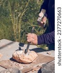 Small photo of From above of crop anonymous craftsman cutting solid rock using sharp chisel and hammer while creating stone craft outside