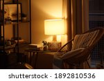 View of a cozy reader's corner with a table lamp spending warm light