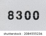 Small photo of Black Number 8300 on the white wall. Spray paint. Number eight thousand three hundred.