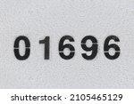 Small photo of Black Number 01696 on the white wall. Spray paint.one thousand six hundred ninety-sixone thousand six hundred ninety-six