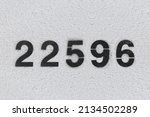 Small photo of Black Number 22596 on the white wall. Spray paint.two hundred and two thousand five hundred ninety-sixtwo hundred and two thousand five hundred ninety-six