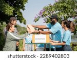 Small photo of Team of volunteers holding donations boxes in outdoor. Volunteers putting food in donation boxes, social worker making notes charity